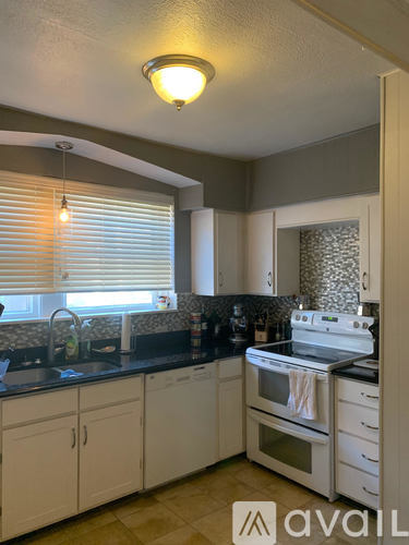 A kitchen with white cabinets and a black countertop.