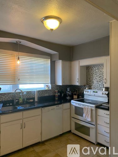 A kitchen with white cabinets and a black countertop.
