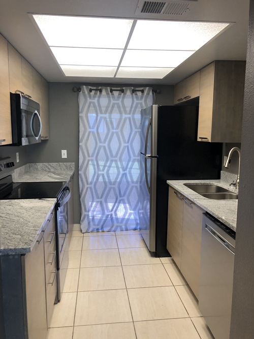 A kitchen with a black refrigerator and a black microwave.