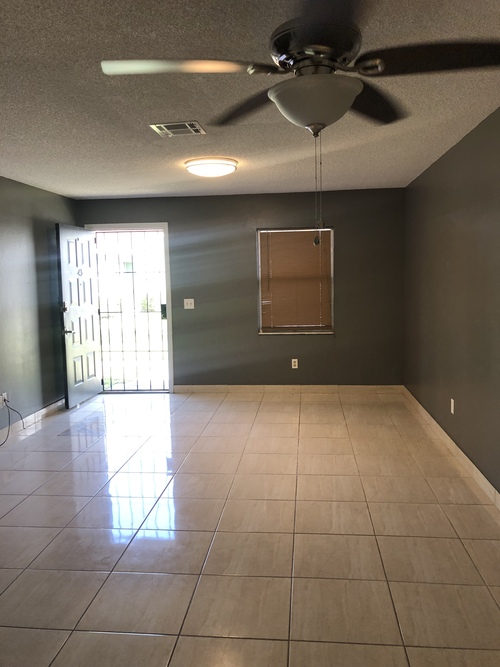 A room with a ceiling fan and tile flooring.