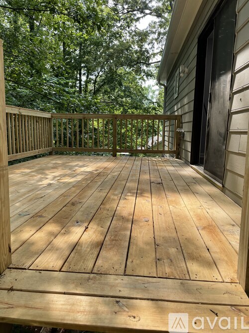 A wooden deck with a railing and trees in the background.