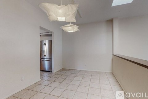 A kitchen with a refrigerator and a tiled floor.