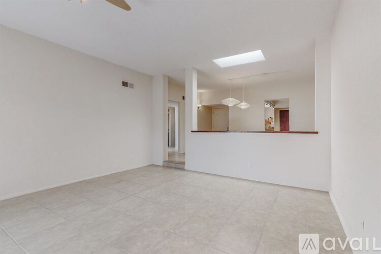 A spacious, empty room with a ceiling fan and tiled flooring.