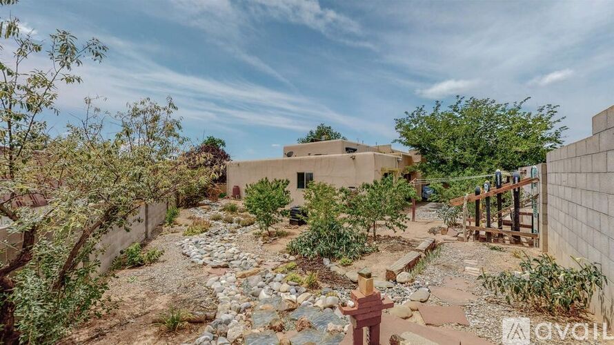 A garden with a stone pathway leading to a building with a wall on one side.