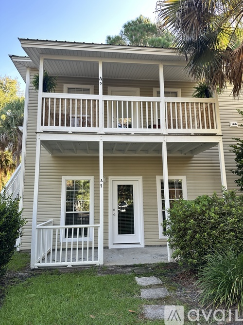 A two-story house with a balcony and a white door.