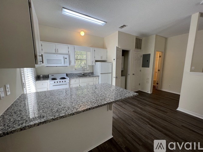 A kitchen with granite countertops and white appliances.