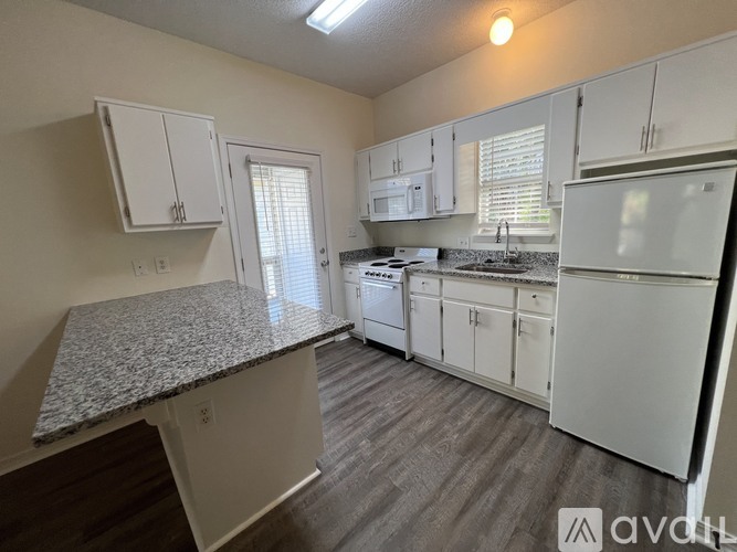 A kitchen with white cabinets and a granite countertop.