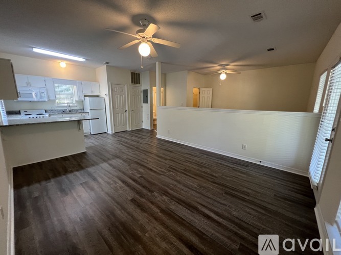 A spacious room with wooden flooring and a ceiling fan.