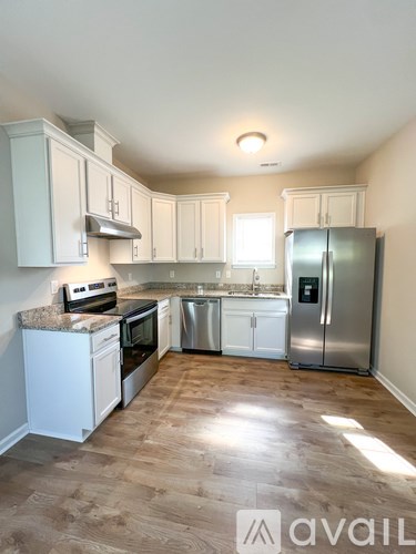 A kitchen with white cabinets and a stainless steel refrigerator.