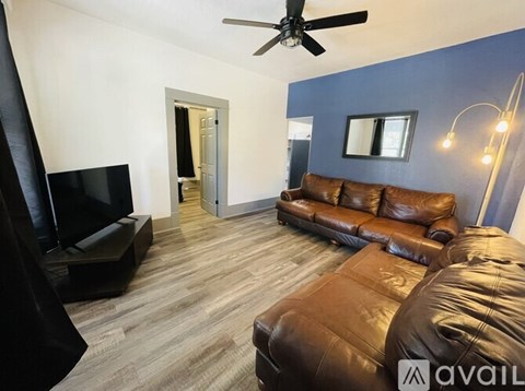 A living room with a brown leather couch and a black television.