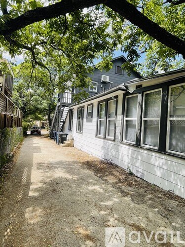 A white house with a grey roof is surrounded by trees.