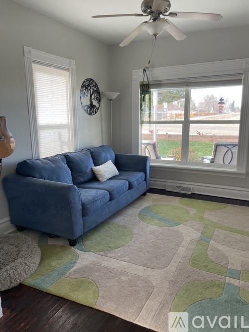 A blue couch sits in a living room with a fan on the ceiling.