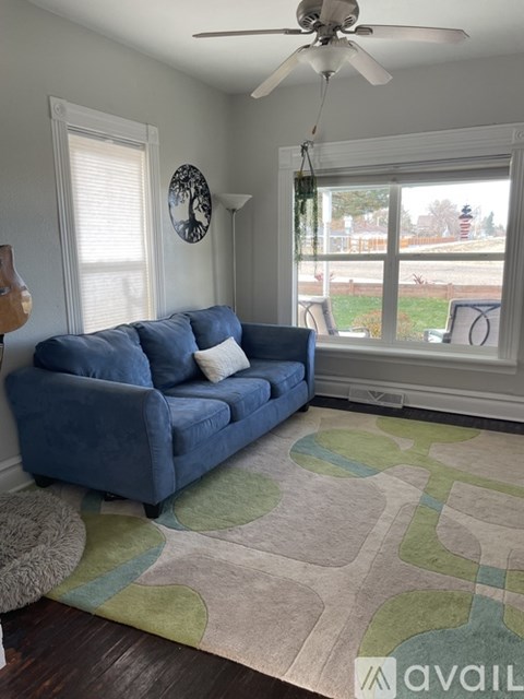 A blue couch sits in a living room with a fan on the ceiling.
