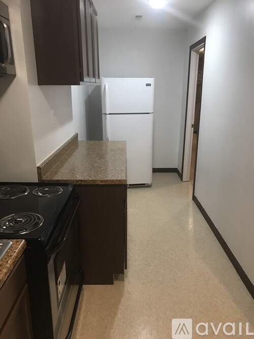 A kitchen with a white fridge and black stove top.