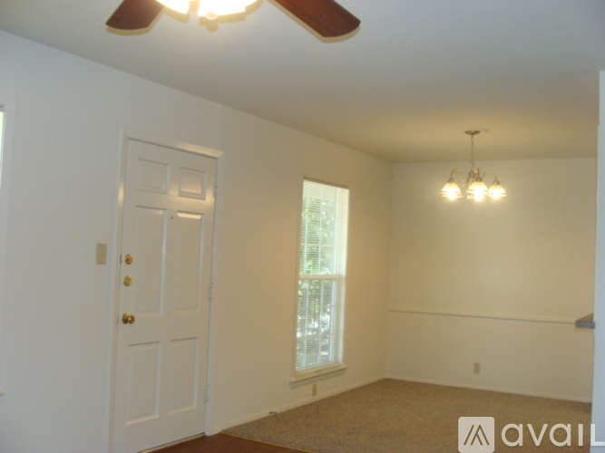 A room with a white door, a window, and a ceiling fan.