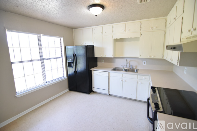 A kitchen with black and white appliances and white cabinets.