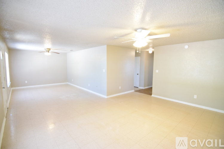 A spacious room with a ceiling fan and a door.