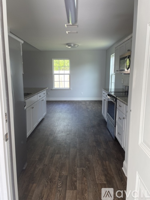 A kitchen with white cabinets and a wooden floor.