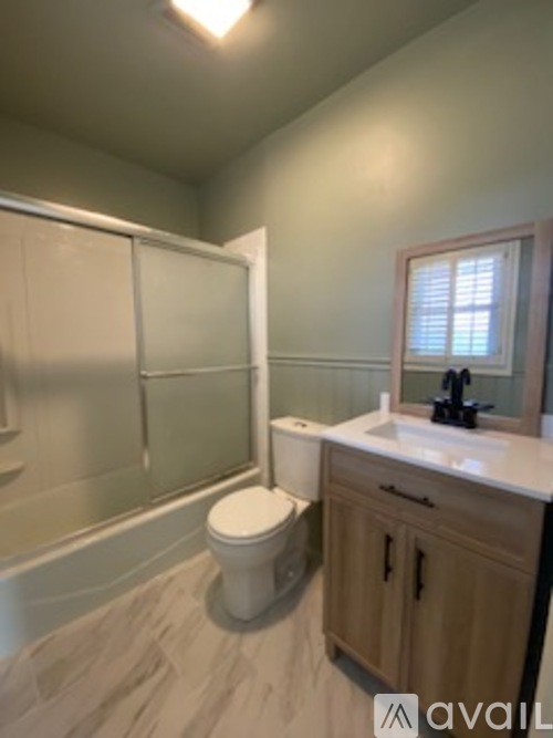 A bathroom with a toilet, sink, and shower.