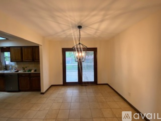 A spacious room with a chandelier and a view of the outdoors through a sliding glass door.