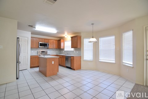 A kitchen with white tile flooring and wooden cabinets.