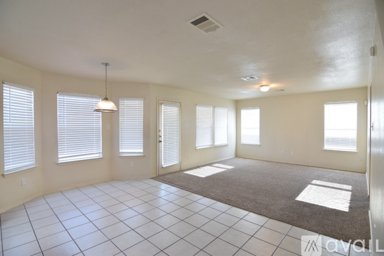 A spacious room with a rug on the floor and a chandelier hanging from the ceiling.