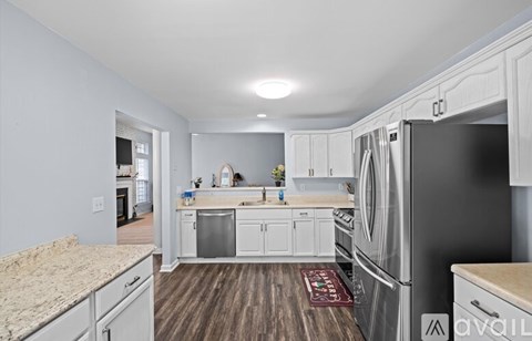 A kitchen with white cabinets and a wooden floor.