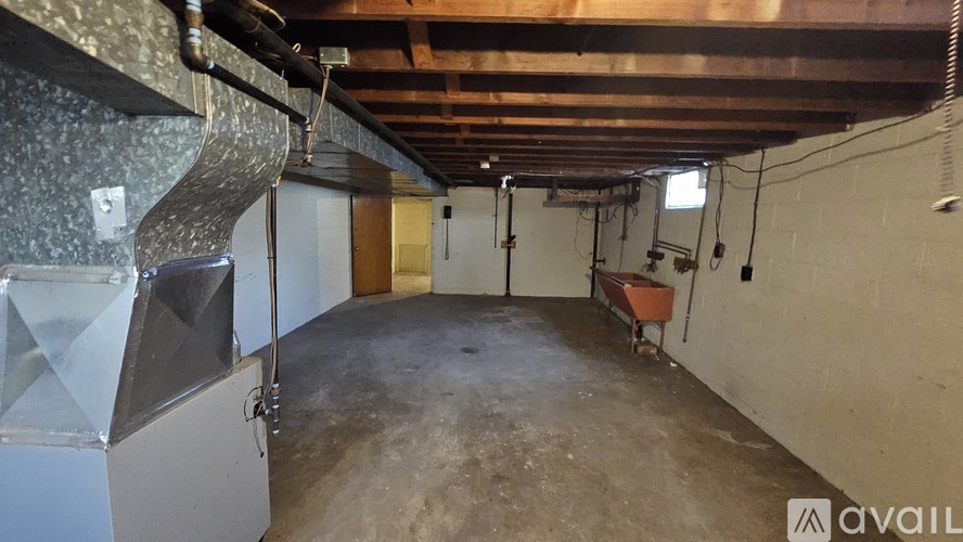 A room with a concrete floor and walls, a white ceiling, and a large metal structure on the left side.