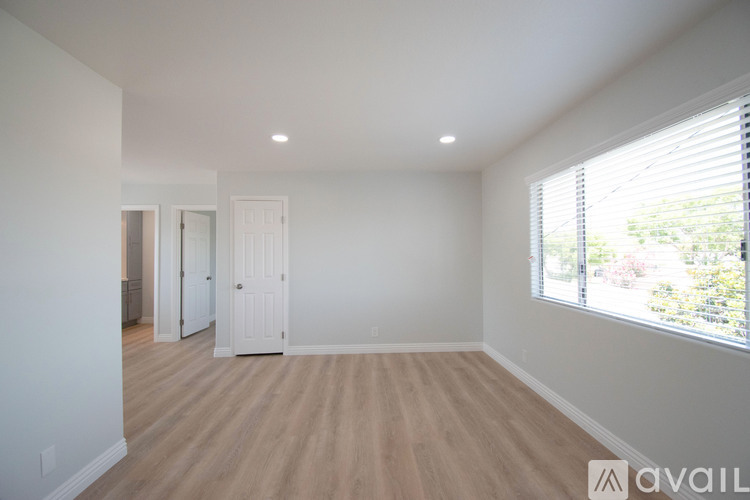 A spacious room with wooden flooring and white walls.
