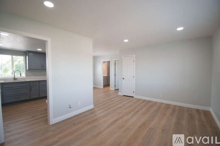 A spacious room with wooden flooring and white walls.