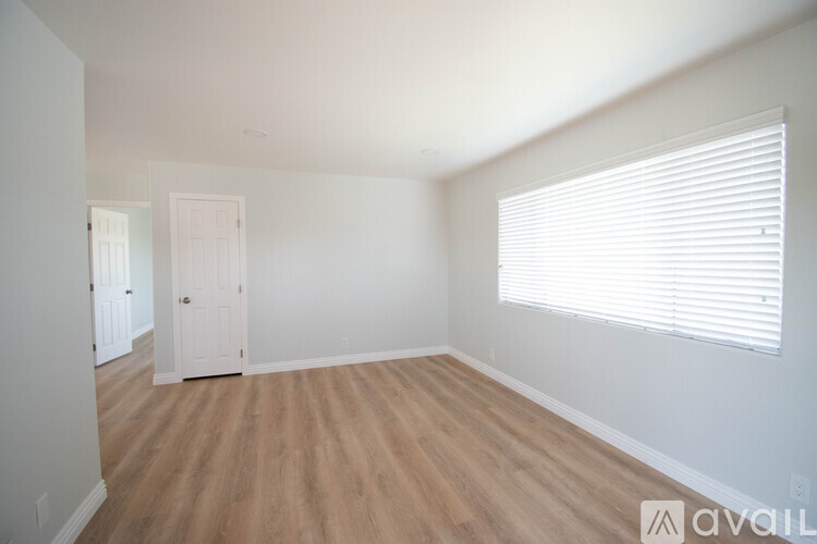 A room with wooden flooring and a window with blinds.