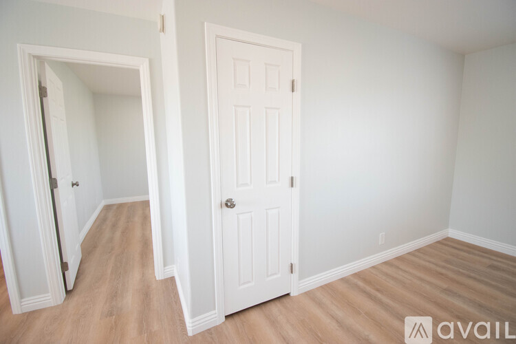 A room with a white door and a mirror on the wall.