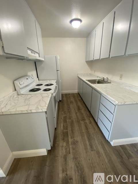 A kitchen with white cabinets and a white stove top oven.