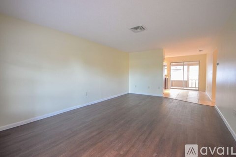 A room with wooden flooring and a doorway leading to another room.