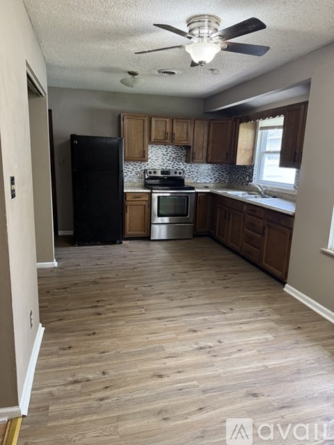 A kitchen with wooden floors and a black refrigerator.
