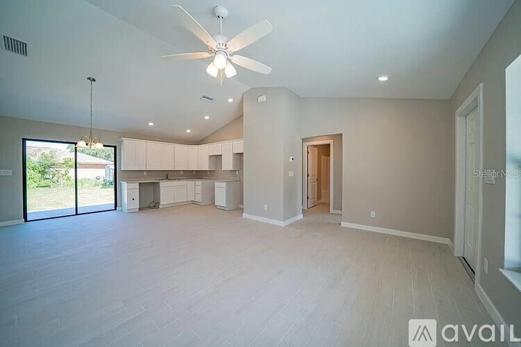 A spacious room with a ceiling fan and sliding glass doors leading to a patio.