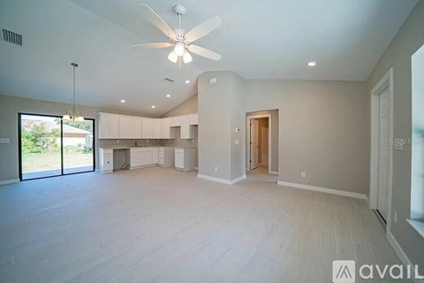 A spacious room with a ceiling fan and sliding glass doors leading to a patio.