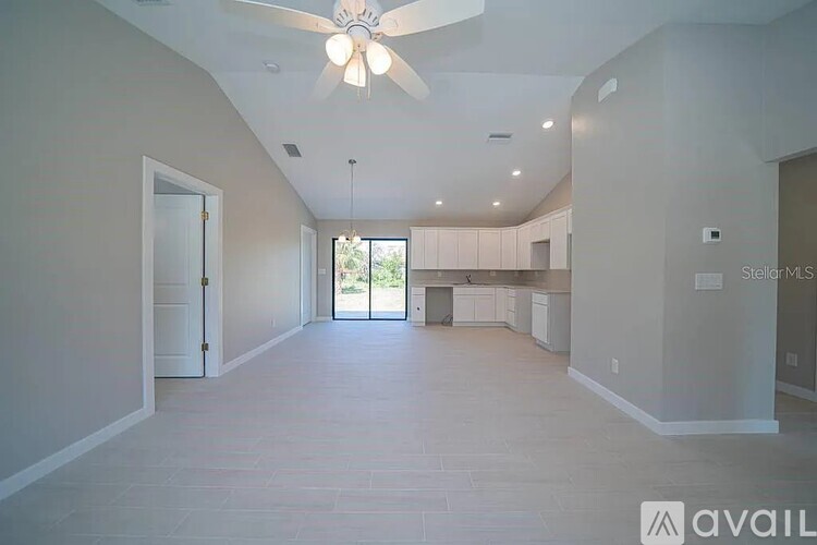 A spacious room with a ceiling fan and a view of the outdoors through a sliding glass door.