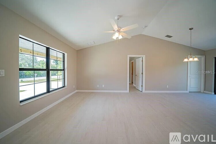 A spacious room with a ceiling fan and large windows.