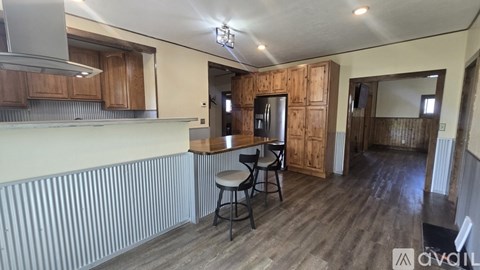 A kitchen with wooden cabinets and a bar stool.