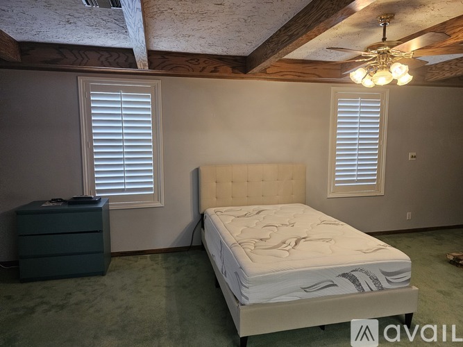 A bedroom with a bed, dresser, and window with blinds.