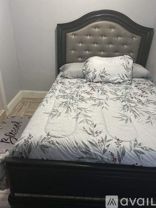 A bed with a floral patterned comforter and a dark headboard.
