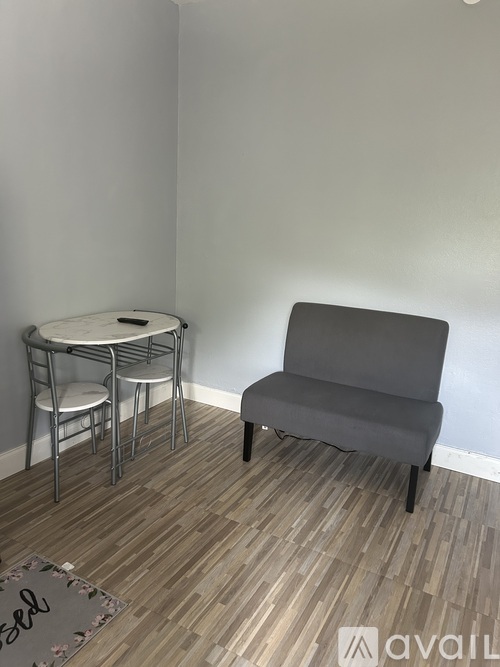 A grey chair sits next to a round table with four chairs around it.