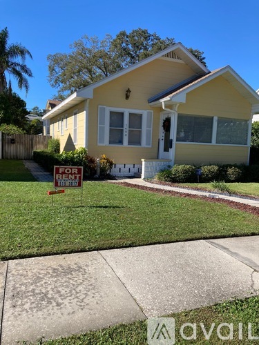 A yellow house with a for sale sign in front.