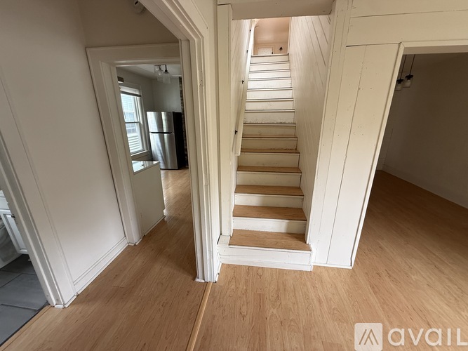 A wooden staircase leads up to a brightly lit room.