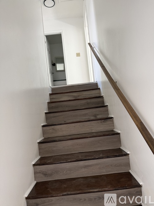 A set of stairs with wooden steps and a brown handrail.