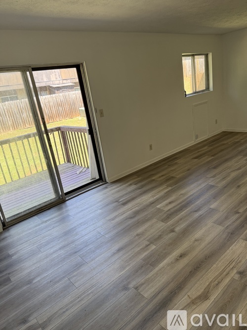 A room with wooden flooring and a sliding glass door leading to a backyard.