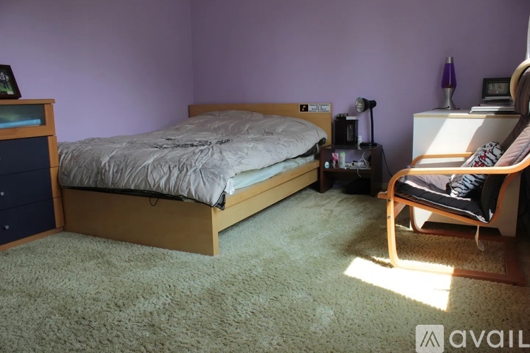 A bedroom with a bed, chair, and nightstand.