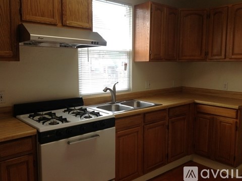 A kitchen with a white stove and wooden cabinets.