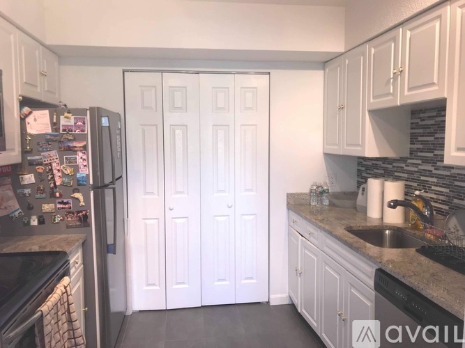 A kitchen with white cabinets and a black fridge.
